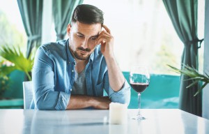 Closeup of early 30's man having some wine in the middle of the day and thinking about his relationship problem. Somewhere at the bottom of the glass there is a meaning of everything that bothers him right now.