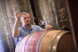 Cropped shot of a sommelier pouring a glass of wine right out the barrel